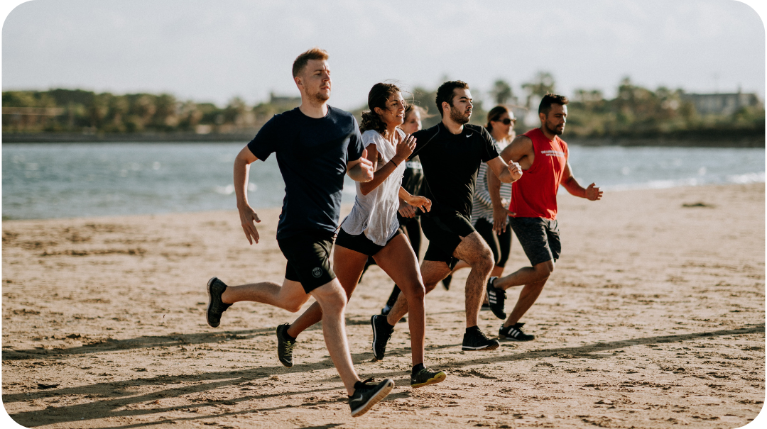 A group of people wearing fitness clothing while running on the beach. 