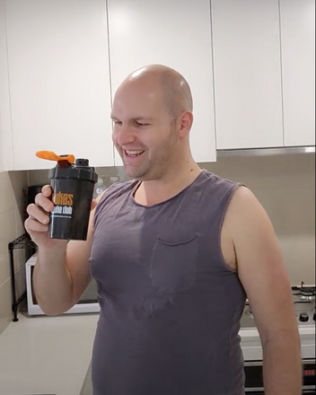 Man looking happy holding a Dukes Protein Shaker inside his kithen