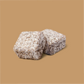 2 pieces of lamingtons lying on top of one another with a light brown background